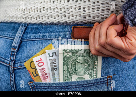 On-line-Geschäft, Gewinne, Reisen und Finanzen Konzept - USD, AUD, EUR und in der Tasche auf der Rückseite der blauen Jeans mit weiblichen Hand erreichen für das Geld Stockfoto