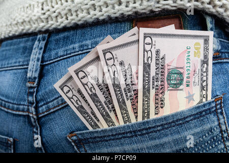 Aktuelle wirtschaft Konzept - US-Dollarnoten in der Tasche auf der Rückseite der Frau trägt blaue Jeans Stockfoto