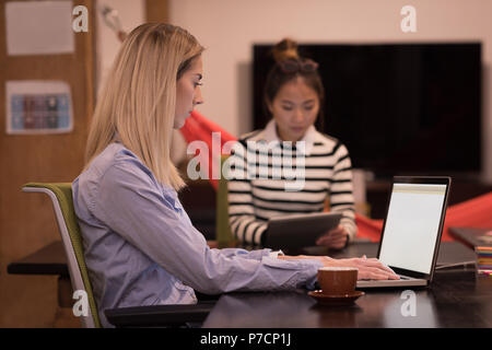 Weibliche Führungskräfte mit Laptop und einer Tablette am Schreibtisch Stockfoto