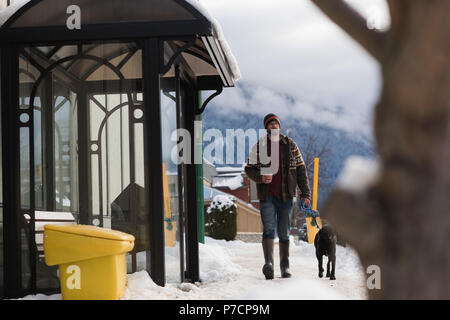 Mann geht mit seinem Hund auf dem Bürgersteig Stockfoto