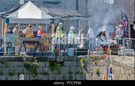 PORTSOY FESTIVAL ABERDEENSHIRE SCHOTTLAND Arbroath Smokies SCHELLFISCH FISCH MANN AN DER RAUCHEN BARREL FISCH AUF DER HAFENMAUER Stockfoto