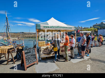 PORTSOY FESTIVAL ABERDEENSHIRE SCHOTTLAND Arbroath Smokies SCHELLFISCH FISCH Menschen kaufen den geräucherten Fisch aus dem Stall Stockfoto