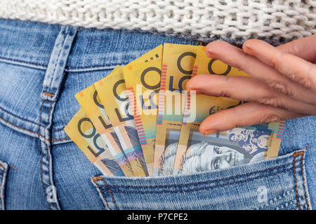 Weibliche Hand erreichen für 50 australische Dollar Scheine in ihre Jeans Gesäßtasche Stockfoto