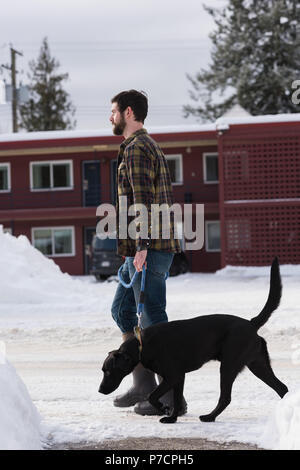 Mann geht mit seinem Hund auf dem Bürgersteig Stockfoto