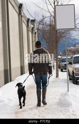 Mann geht mit seinem Hund auf dem Bürgersteig Stockfoto