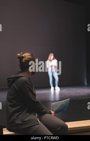 Weibliche Schauspielerin lesen Skript während männliche Schauspieler ihr auf der Bühne Stockfoto