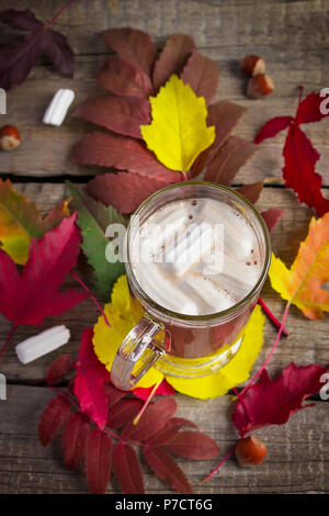 Kakao mit Marshmallows vor dem Hintergrund der hellen Blätter im Herbst. Stockfoto