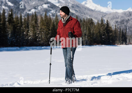 Man Walking mit skistock in verschneiter Landschaft Stockfoto