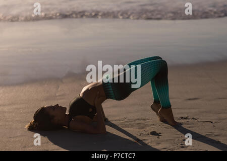 Passende Frau durchführen Yoga am Strand Stockfoto