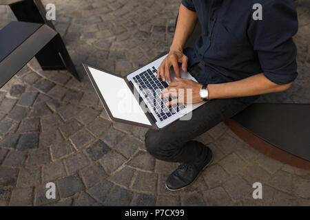 Geschäftsmann mit Laptop im Straßencafé Stockfoto