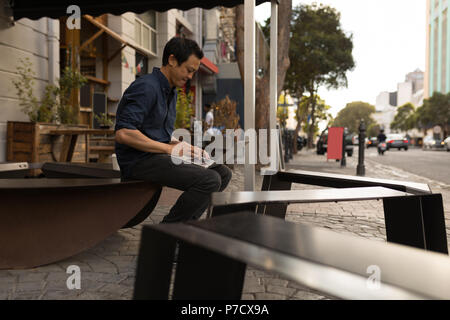 Geschäftsmann mit Laptop im Straßencafé Stockfoto