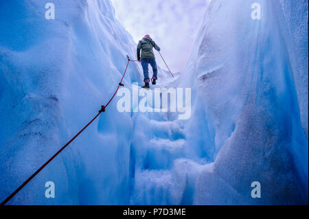 Frau wenige Schritte aus einer Eishöhle in Fox Glacier, South Island, Neuseeland Stockfoto