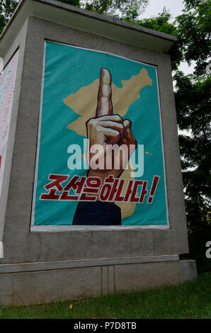 Plakat auf der nordkoreanischen Seite der DMZ mit einem Finger, einem Land, Wiedervereinigung, das Ziel. Stockfoto