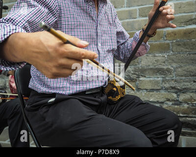 Chinesischer Mann spielt die chinesische Geige genannt Erhu in einem kleinen Ensemble outdoor im Tempel des Himmels Stockfoto