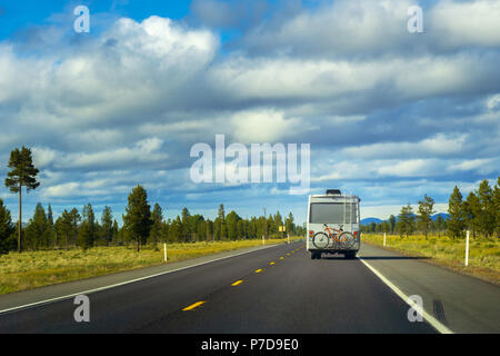 Recreational Vehicle mit Bike hängen auf der Rückseite der Fahrt durch die Landschaft. Reisen und Fernweh Konzept Bild mit kopieren. Stockfoto