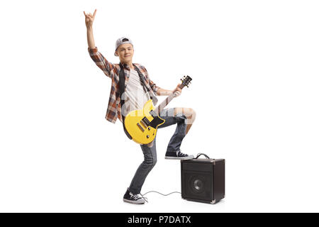 In voller Länge Porträt eines Jugendlichen mit einer E-Gitarre und Verstärker ein Rock Geste auf weißem Hintergrund Stockfoto