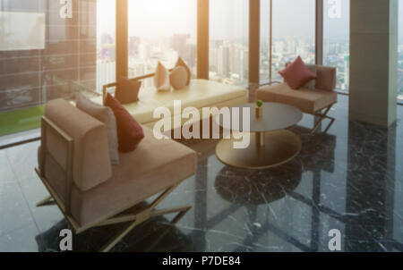 Blured der modernen Sofa und Gebäude Glas auf Turm in Wohnzimmer mit städtischen Skyline Gebäude Hintergrund und die warme Sonne am Nachmittag Zeit. Stockfoto