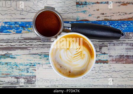 Eine Tasse Latte, Cappuccino oder Espresso Kaffee mit Milch auf einem Holztisch mit dunkel geröstete Kaffeebohnen Stockfoto