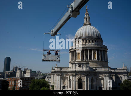 Fenster Reiniger sind in einer Wiege vor einem Bürogebäude neben der St. Paul's Cathedral in London, Großbritannien, 3. Juli 2018 ausgesetzt. Stockfoto