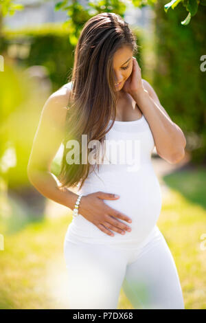 Glücklich schwanger Frau, Outdoor, Hände auf Bauch Stockfoto