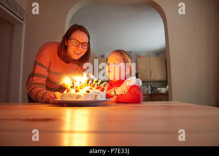 Mutter und Kind Tochter Ausblasen Geburtstag Kerzen am Küchentisch Stockfoto
