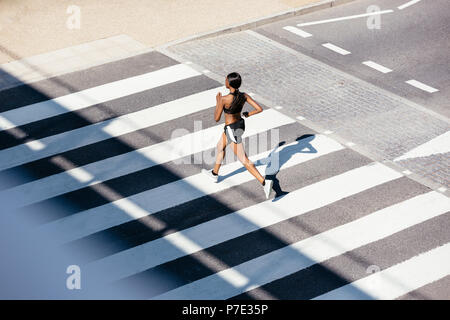 Junge Frau, die auf Zebrastreifen Stockfoto