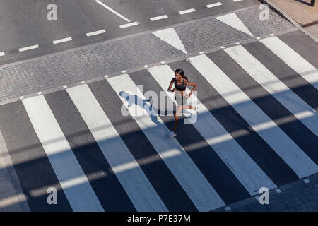 Junge Frau, die auf Zebrastreifen Stockfoto