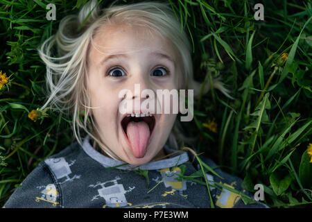 Blonde junge liegend auf Gras klebt die Zunge heraus, Porträt Stockfoto