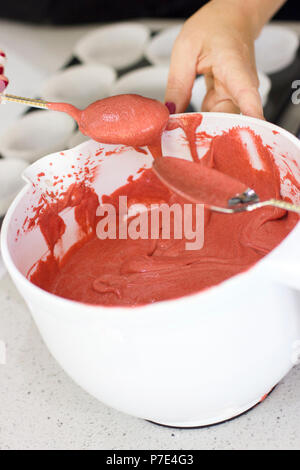 Hand ein rosa Teig in eine weiße Schale mit Löffel rühren Stockfoto