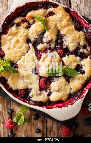 Warme Süße Schuster von Himbeeren und Blaubeeren close-up in einer Auflaufform auf einem Tisch. Senkrechte Draufsicht von oben Stockfoto