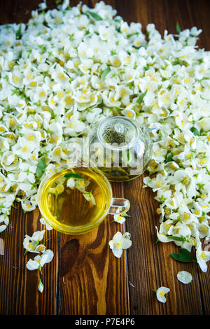 Tee mit jasminblüten in einer Teekanne aus Glas auf einem Tisch Stockfoto