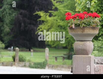 Ein Blumengebinde auf einem alten Stein Spalte vor der Schlosspark Stockfoto