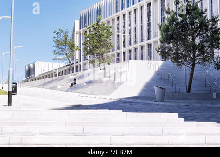 Eine kleine Zahl von Eine nicht erkennbare junge Frau sitzt auf den Stufen des neuen Stadt Glasgow College in Glasgow, Schottland, Großbritannien Stockfoto