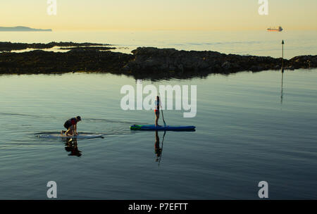 29. Juni 2018 Ein paar langsam ihre Surfbretter Paddel in das ruhige Meer am Hafen in der Nähe der Groomsport Bangor Northern Ireland in einer ruhigen und warmen Sommer Eva Stockfoto