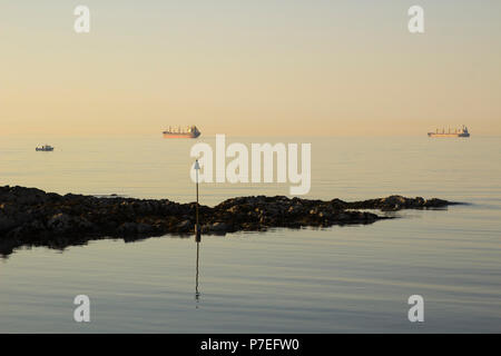 Schiffe vor Anker an der Mündung des Belfast Lough, wie die Sonne über dem Eingang Groomsport Dorf Hafen in Nordirland Stockfoto