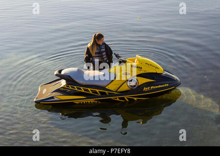 29. Juni 2018 eine junge Frau in einen Taucheranzug wartet auf Ihren Partner neben einem leistungsstarken Yamaha Jet-Ski auf der Helling in Groomsport Hafen Nordirland Stockfoto