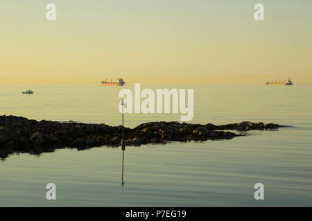 Schiffe vor Anker an der Mündung des Belfast Lough, wie die Sonne über dem Eingang Groomsport Dorf Hafen in Nordirland Stockfoto