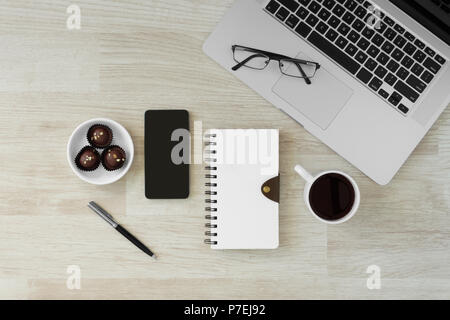 Laptop und Notebooks mit heißem Kaffee und Cookies auf Holz Hintergrund. Morgen rustikal Home Office. Stockfoto
