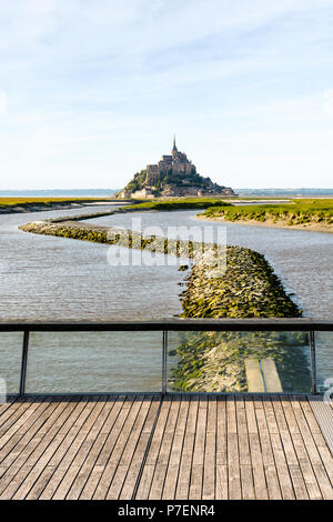 Blick auf den Mont Saint-Michel tidal Island in der Normandie, Frankreich, bei Flut mit der Fußgängerbrücke über den Damm auf der Couesnon river im Vordergrund. Stockfoto