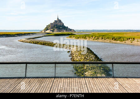 Blick auf den Mont Saint-Michel tidal Island in der Normandie, Frankreich, bei Flut mit der Fußgängerbrücke über den Damm auf der Couesnon river im Vordergrund. Stockfoto