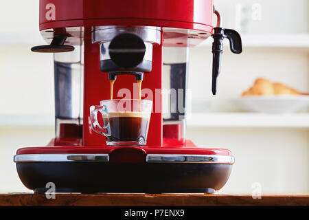Einen frischen Kaffee aus einer Kaffeemaschine Espressomaschine. Die Espresso in Glas transparent Kaffeetasse. Stockfoto