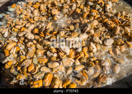 Frische Muscheln im Grill Pfanne. Seafood Grill im Freien. Picknick gesundes Essen, Muscheln ohne Schale. Fisch, Gegrilltem appetitlich Muscheln auf einer schwarzen Platte. Stockfoto