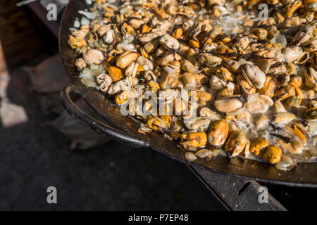 Frische Muscheln im Grill Pfanne. Seafood Grill im Freien. Picknick gesundes Essen, Muscheln ohne Schale. Fisch, Gegrilltem appetitlich Muscheln auf einer schwarzen Platte. Stockfoto