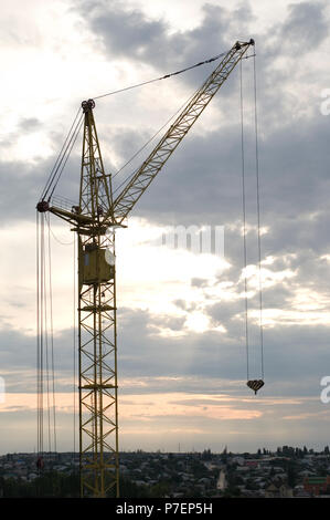 Industriebau-Krane und Gebäude Silhouetten über Sonne bei Sonnenaufgang. Stockfoto