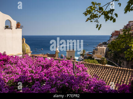 Positano durch rosafarbene Bougainvillea und Boote im Hintergrund eingerahmt. Bunte Positano, das Juwel der Amalfi Küste, mit seinen bunten Häusern und Stockfoto