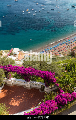Positano durch rosafarbene Bougainvillea und Boote im Hintergrund eingerahmt. Bunte Positano, das Juwel der Amalfi Küste, mit seinen bunten Häusern und Stockfoto