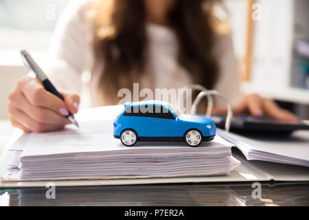 Geschäftsfrau Arbeiten an Dokumenten mit kleinen blauen Auto Stockfoto