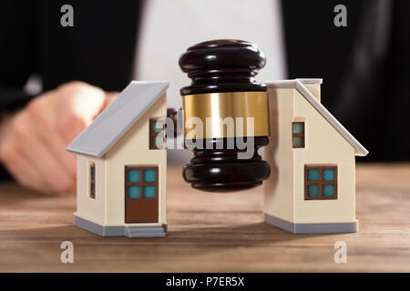 Nahaufnahme eines Richters markante Hammer zwischen Split Haus über Holz- Schreibtisch Stockfoto