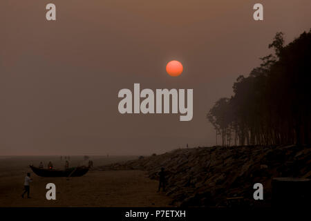 Sonnenuntergang in der Dämmerung trübe Meer Strand mit roter Sonne und grüne Bäume Stockfoto