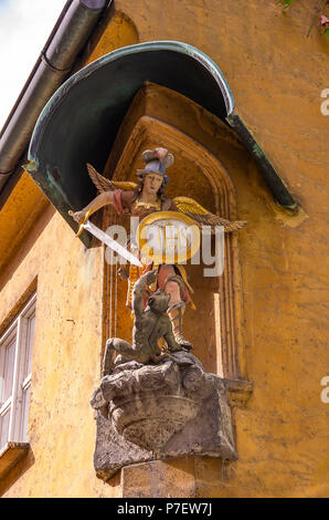 Fuggerei, Augsburg, Bayern, Deutschland - Darstellung des Erzengels Michael im Kampf gegen die Teufel an der Ecke eines Hauses. Stockfoto